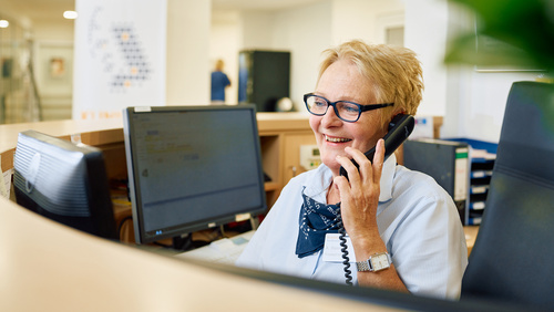 Eine Mitarbeiterin der Information telefoniert hinter ihrem Tresen. 